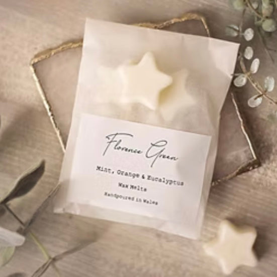 Packet of mint, orange and eucalyptus vegetable wax melts from Florence green on a beige background.