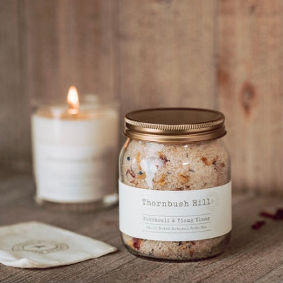 Glass jar of Thornbush Hill Patchouli and Ylang Ylang Bath Tea with decorative background