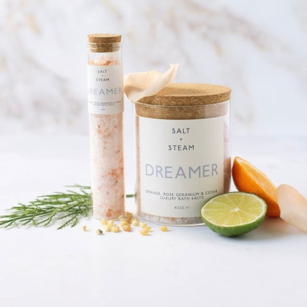 zesty dreamer vegan bath salts from British brand Salt and steam on a white background with added lime and orange fruit within image